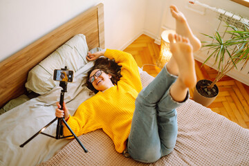 Beautiful fashion blogger holding yellow sweater dreamily recording new fashion video for vlog....