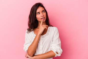 Fototapeta premium Young caucasian woman isolated on pink background looking sideways with doubtful and skeptical expression.