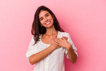 Young caucasian woman isolated on pink background has friendly expression, pressing palm to chest. Love concept.