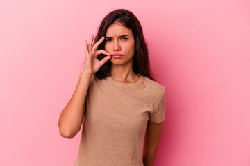 Fototapeta premium Young caucasian woman isolated on pink background with fingers on lips keeping a secret.