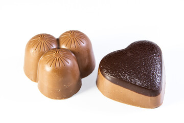 Two milk chocolates, one heart shaped and the other triple shaped on white background