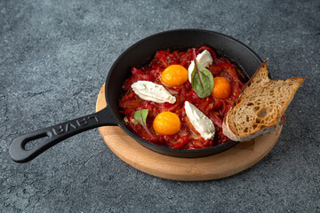 Fried eggs with tomatoes and onions. Ready menu for the restaurant. Neutral gray blue textured background