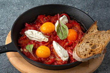 Fried eggs with tomatoes and onions. Ready menu for the restaurant. Neutral gray blue textured background