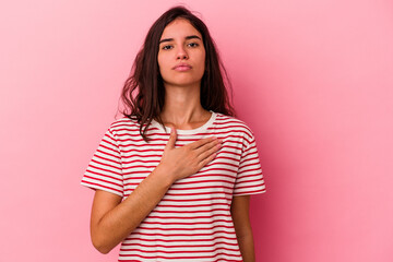 Fototapeta premium Young caucasian woman isolated on pink background taking an oath, putting hand on chest.