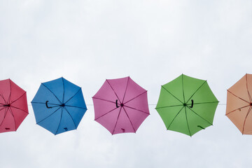 Three colorful umbrellas floating in the cloudy sky