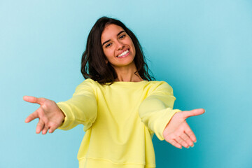 Young caucasian woman isolated on blue background showing a welcome expression.