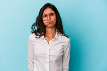 Young caucasian woman isolated on blue background blows cheeks, has tired expression. Facial expression concept.