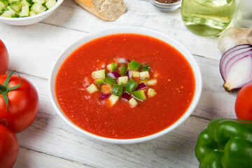 Gazpacho. Traditional Spanish tomato soup with fresh tomatoes, cucumber, bell pepper on a white rustic wooden table.
