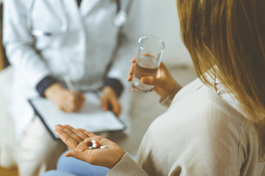 Close-up woman-patient holding pills near her doctor, time to take medications, cure for headache or remedy pain killer drugs. Stay at home concept during Coronavirus pandemic and self isolation