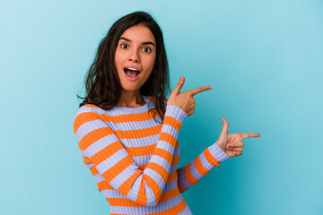 Young caucasian woman isolated on blue background excited pointing with forefingers away.