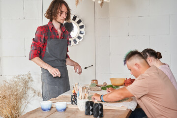 Sculptor wearing apron looking attentively while teaching his master class - Powered by Adobe