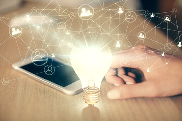 Double exposure of light bulb hologram and woman holding and using a mobile device. Idea concept.
