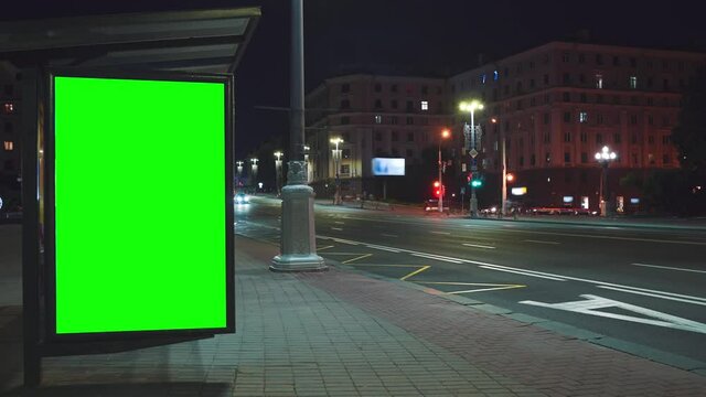 Chroma key advertising billboard with green screen on bus stop at night. High quality 4k footage