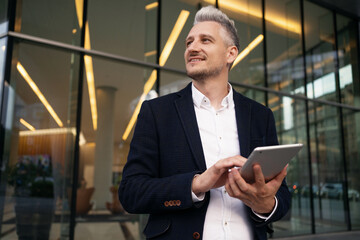 The manager is sitting near the business center typing on a tablet. A man of European appearance is...