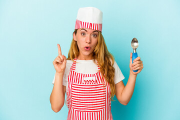 Caucasian ice cream maker woman holding an ice cream scoop isolated on blue background having some great idea, concept of creativity.