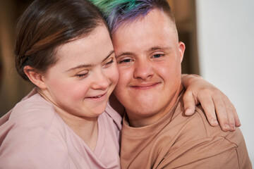 Boy with special needs embracing tight his girlfriend and looking at the camera