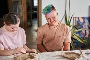 Boy with down syndrome smiling happily and looking at the dishes