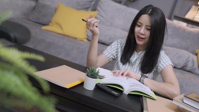 Close up a young mixed race student does homework, writes on paper, studies remotely from home in quarantine online, female fast learner enjoying her weekend with preparing educational lesson