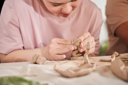 Woman with special needs working with clay in ceramic studio during the pottery workshop