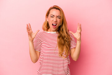 Caucasian blonde woman isolated on pink background screaming with rage.