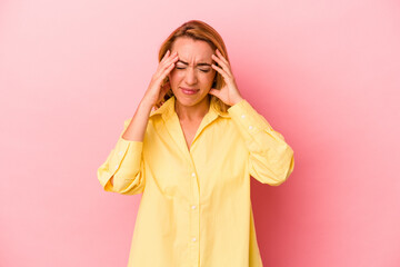 Caucasian blonde woman isolated on pink background touching temples and having headache.