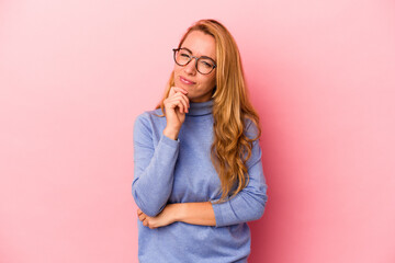 Caucasian blonde woman isolated on pink background thinking and looking up, being reflective, contemplating, having a fantasy.