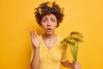 Puzzled young African American woman suffers from hay fever looks shocked at camera has allergic...