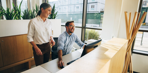 Business people looking at computer and smiling