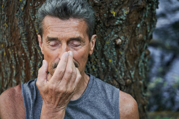 Man practicing breathing yoga pranayama while sitting at the mat outdoors