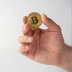 Close-up of a man holding a gold-colored bitcoin coin. White background, Cryptocurrency Concept