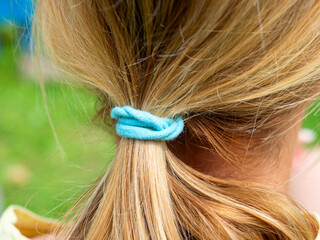 close up blue elastic band on her blond hair in a bun