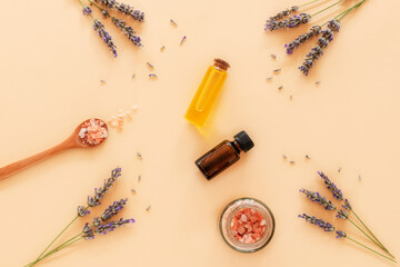 Lavender blossom, himalayan pink salt and essential oils on beige background, top view, flat lay