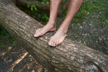 Senior man keeping his legs at the tree trunk while relaxing at the forest