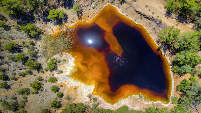 Acidic red lake in place of abandoned open pit copper mine near Kinousa, Cyprus. Aerial view from directly above