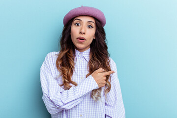 Young mexican woman isolated on blue background smiling and pointing aside, showing something at blank space.