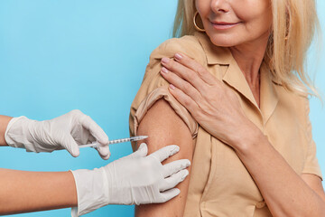Unknown doctor makes insulin or flu vaccination shot to female patient holds syringe with dose of vaccine. Woman gets inoculation in shoulder protects herself against coronavirus. Health care