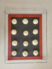 12 raw cookie dough om silicone mat on wire metal baking rack