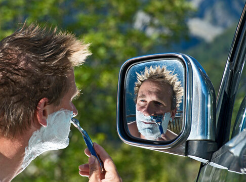 Man Shaving In The Side Mirror Of His Car On Roadtrip