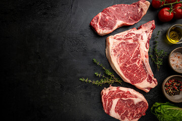 Variety of Fresh Raw Black Angus Prime Meat Steaks T-bone, New York, Ribeye and seasoning on black...