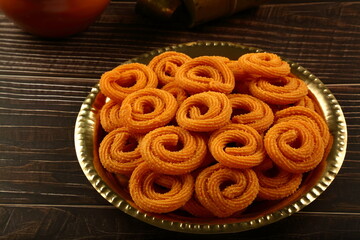 Homemade delicious and spicy oil fried chakli ,murukku, muruku, on a rustic kitchen table background.