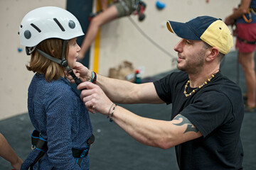 climbing coach helping girl adjusting climbing helmet