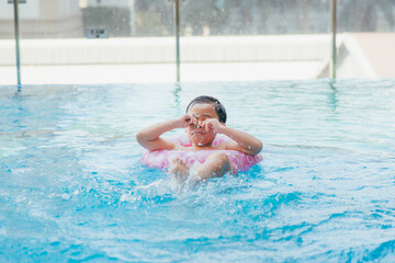 Child at the swimming pool steps, rubbing water from his eyes.