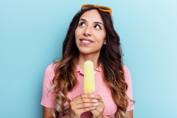 Young latin woman holding an ice cream isolated on blue background