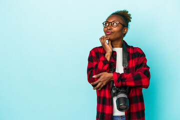 Young photographer african american woman isolated on blue background relaxed thinking about something looking at a copy space.