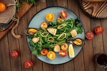 Plate of gourmet seafood salad with greens on a wooden background