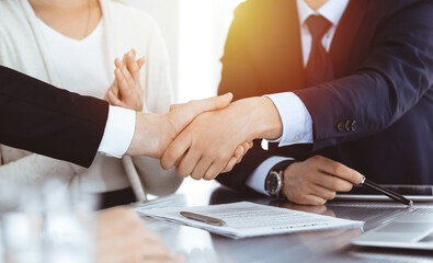 Business people shaking hands after contract signing in sunny modern office. Teamwork and handshake concept