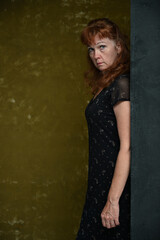 Fototapeta premium Adult serious Caucasian woman looks into the camera. Vertical portrait on dark background