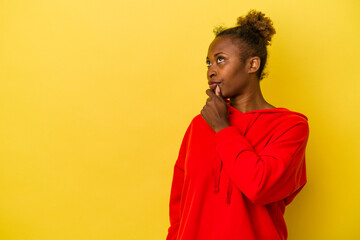 Young african american woman isolated on yellow background relaxed thinking about something looking at a copy space.
