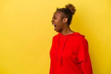 Young african american woman isolated on yellow background shouting very angry, rage concept, frustrated.