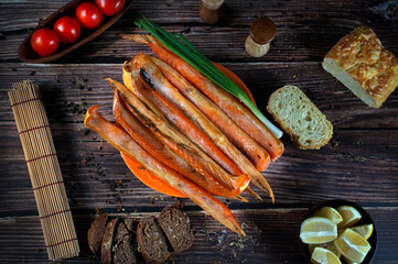 Smoked salmon bellies with vegetables and bread top view on dark background